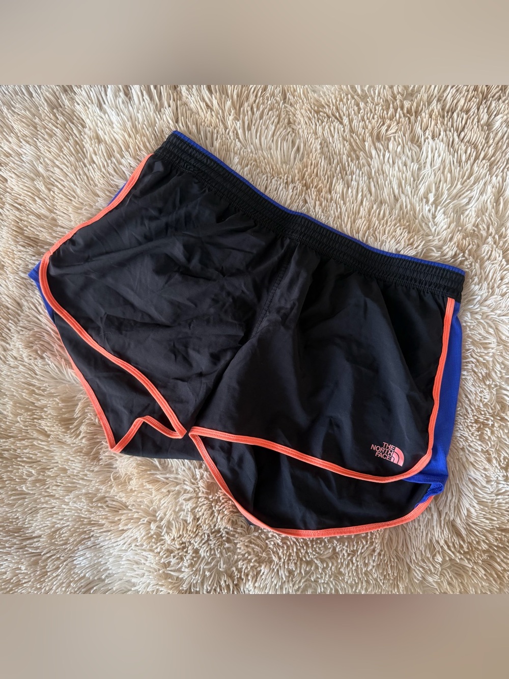 The North Face Women’s Black Athletic Shorts with Orange and Blue trim.
